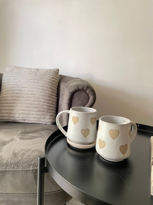 Tall white ceramic mug with handle adorned with stoneware finish heart motifs all over. microwave & dishwasher safe. Perfect for daily use & gifting
