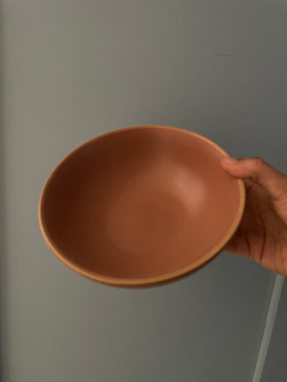 Hand holding stoneware terracotta glazed bowl, subtle tonal rim, 7" diameter. Indulge in handmade bowls in India.