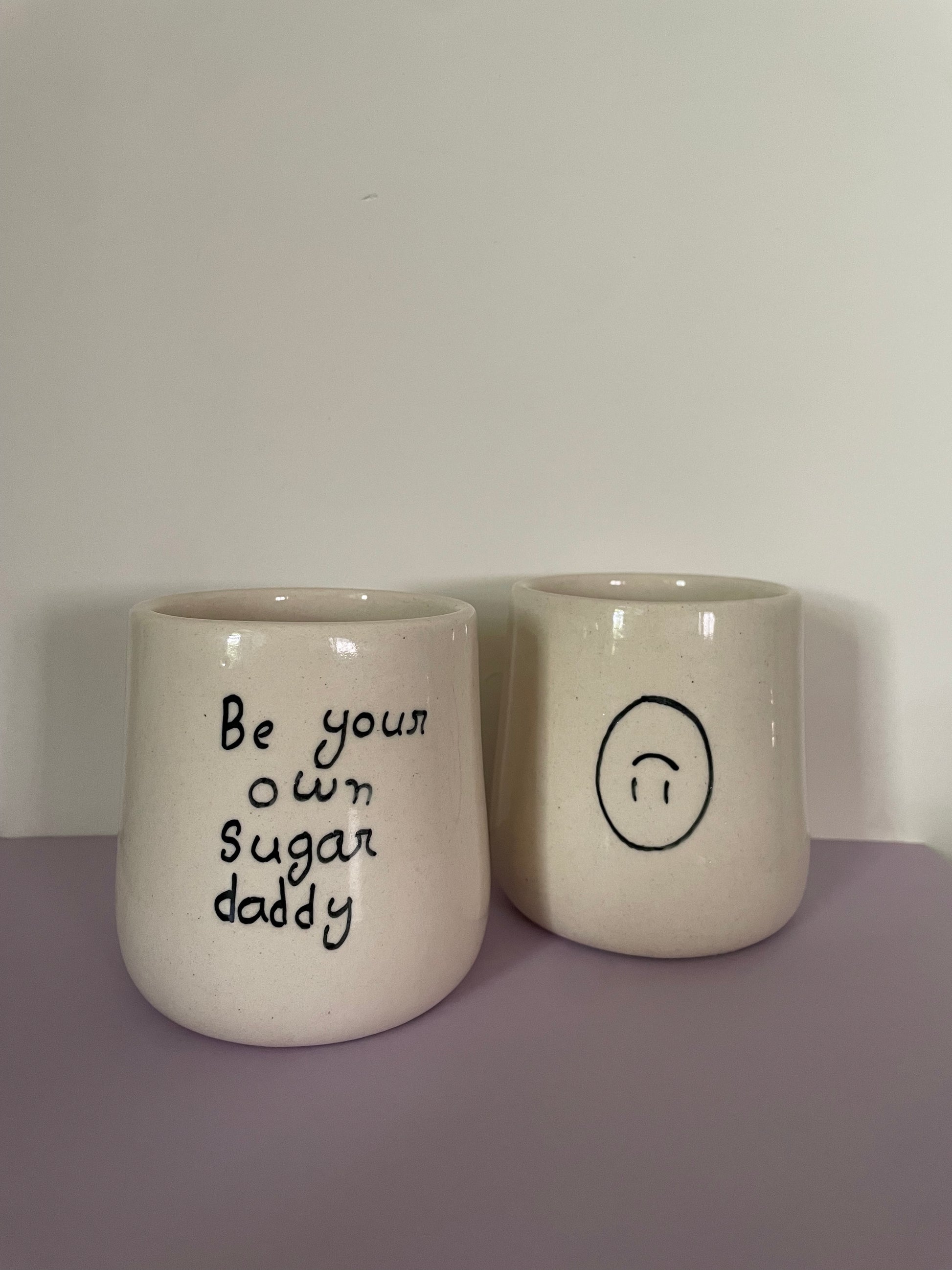 Ceramic mugs without handle, featuring "be your own sugar daddy" and an upside down smiley. Shop artistic ceramics Bangalore