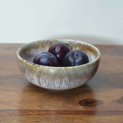 Small ceramic bowl, light pink glaze with brown drip from rim, plums inside. Discover home decor gifts in India.